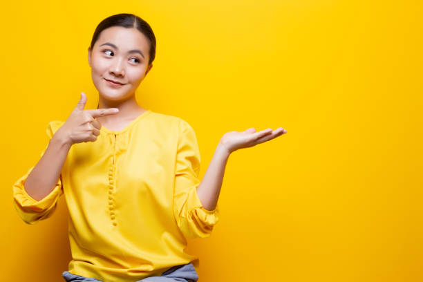 istock Woman pointing to copy space isolated over yellow background 1132674565