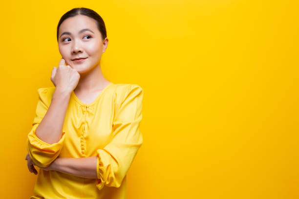 istock Happy woman thinking and standing isolated over yellow background 1132675250