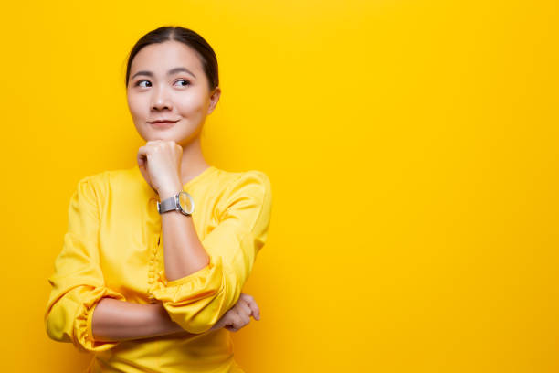 Happy woman thinking and standing isolated over yellow background