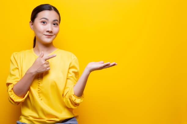 istock Woman pointing to copy space isolated over yellow background 1132675359