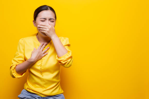 istock Woman has sore throat isolated over yellow background 1132676233
