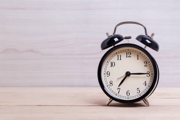 istock A Black Retro alarm clock on wooden board with wood background 1132676357