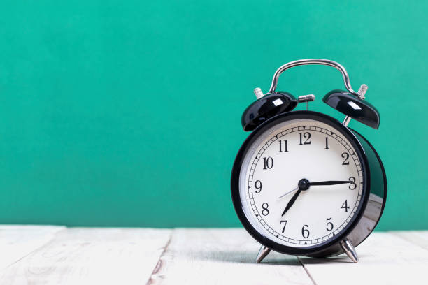 istock A Black Retro alarm clock on wooden board with green background 1132676390