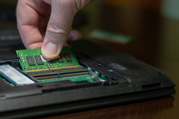 Close-up of male hand puts the RAM into the rear compartment of the laptop. Close-up of male hand puts the RAM into the rear compartment of the laptop. Selective focus. motherboard ram slots stock pictures, royalty-free photos & images