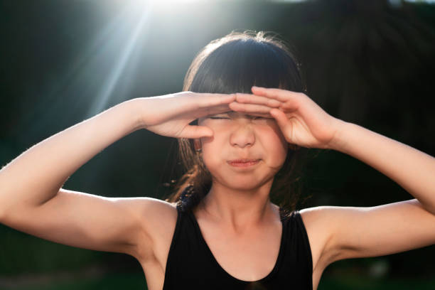 istock Cute girl shielding eyes in yard on sunny day 1132682636