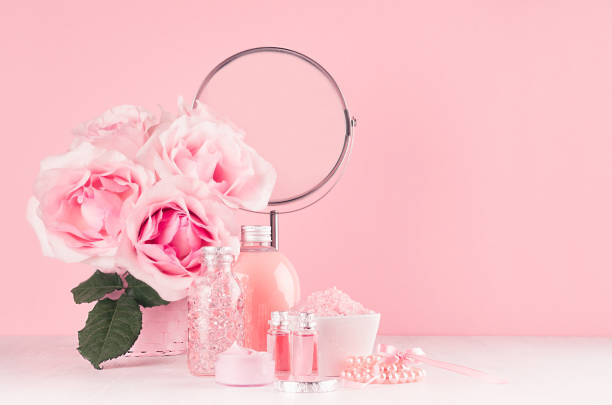 istock Romantic bathroom interior in pastel pink and silver color - flowers, round mirror,  bath accessories, cosmetic products - cream, salt, rose oil, soap on white wood table. 1132685217