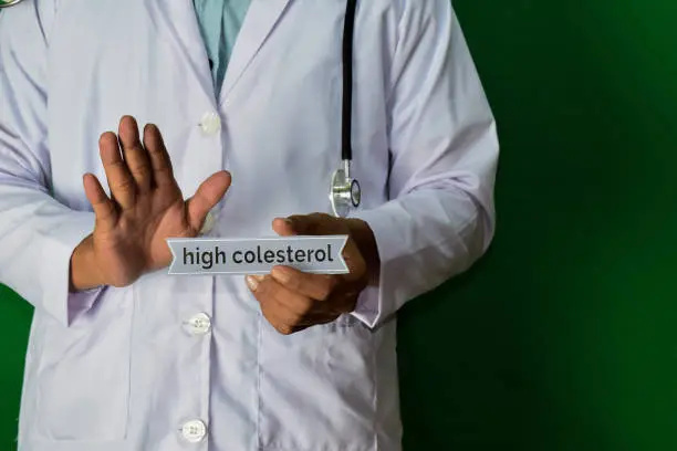 doctor standing on Green background. Selective focus in hand. High Colesterol paper text. Medical and healthcare concept.
