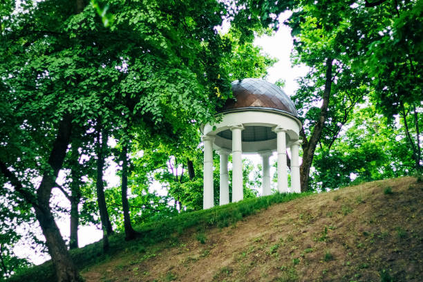 Stone rotunda on a hill in Gomel Park among trees with green foliage