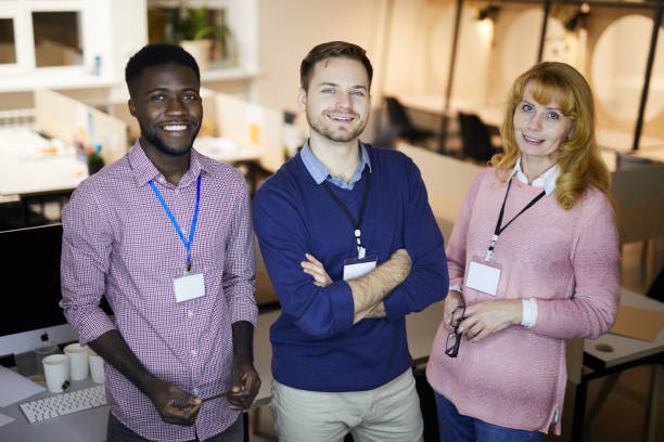 istock Group of positive confident multi-ethnic team with conference badges on becks standing in office and looking at camera 1132703773
