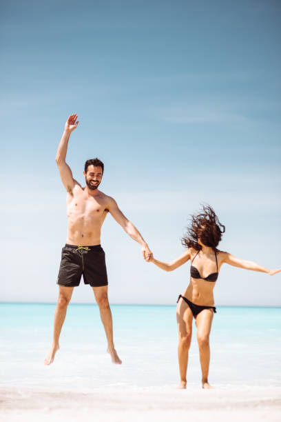 istock jumping couple at the beach 1132706566