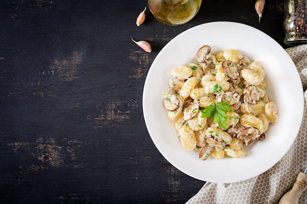 gnocchi mit einer pilzcreme-sauce und petersilie in schüssel auf dunklem hintergrund. top view - kartoffelknödel essen stock-fotos und bilder