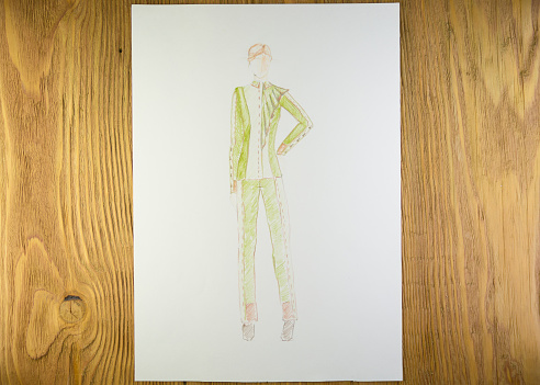 the drawing of designer clothes pencils on paper. background wooden table.