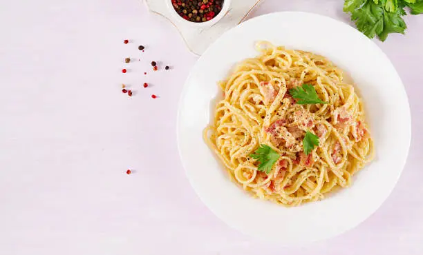 Classic homemade carbonara pasta with pancetta, egg, hard parmesan cheese and cream sauce. Italian cuisine. Spaghetti alla carbonara. Top view, flat lay, copy space