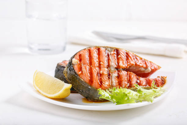 grilled red salmon steak served with lemon and lettuce on white plate. sockeye salmon, kokanee salmon or oncorhynchus nerka. - alaskan salmon imagens e fotografias de stock