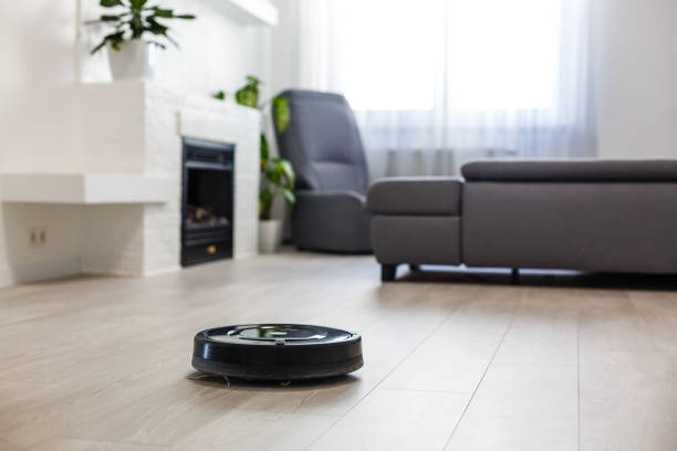 Robotic vacuum cleaner on laminate wood floor in living room Robotic vacuum cleaner on laminate wood floor in living room airtight photos stock pictures, royalty-free photos & images