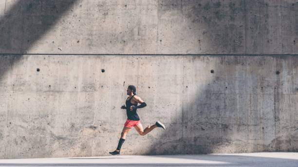 istock Muscular man athlete sprinter running fast,exercising outdoors,jogging outside against gray concret background with copy space area for text message or ad content.Side view,full length. 1132714687