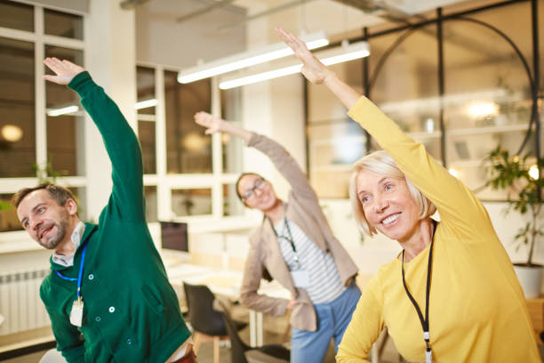 Active company employees exercising in office stock photo