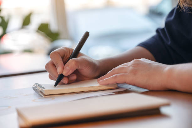 istock Closeup image of a hand writing on blank notebook on wooden table 1132719940