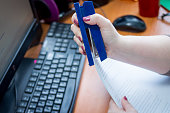 Detail of female hands holding a stapler and filling it with the staples. Hands holding stapler and paper.Close up of a woman hands and holding a blue stapler in her hand. Concept of personal assistant work