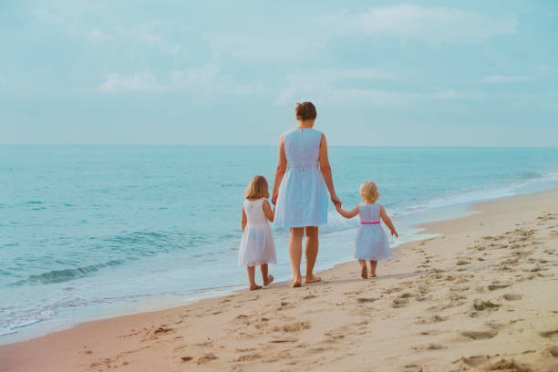 istock mother with little daughters walk on beach 1132727265