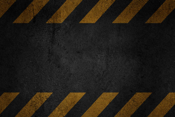 istock Old black grungy asphalt surface with yellow warning stripes 1132728063