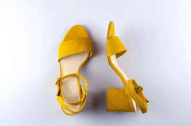 Photo of Two sandals mustard color gray background.