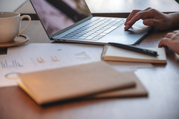 istock Closeup image of a woman's hand using and touching on laptop touchpad with notebooks and papers on the table in office 1132729101