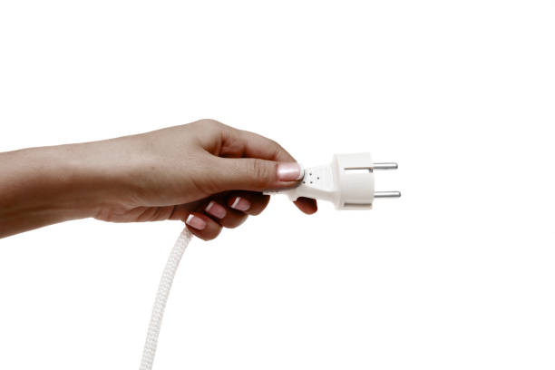 istock African female hand holds electric plug on a white background. 1132731576