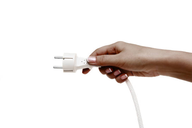 istock African female hand holds electric plug on a white background. 1132731627