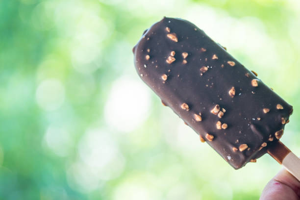 istock Ice cream in chocolate with nuts on stick in hand 1132733160