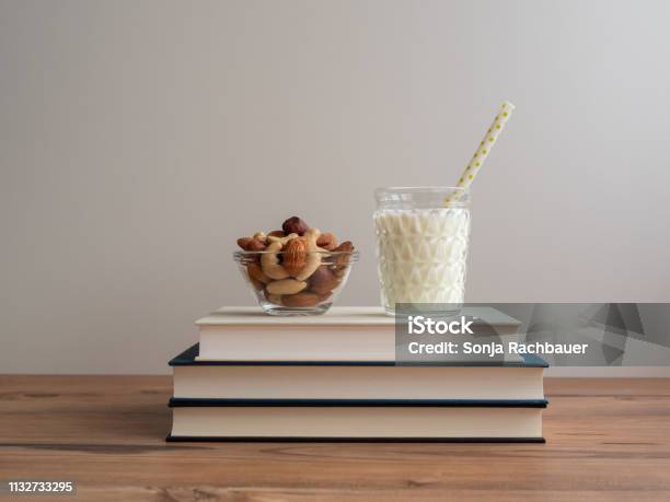 Bust Stack With A Glass Of Milk And A Bowl Of Nuts Stock Photo - Download Image Now - Trail Mix, White Background, Arts Culture and Entertainment