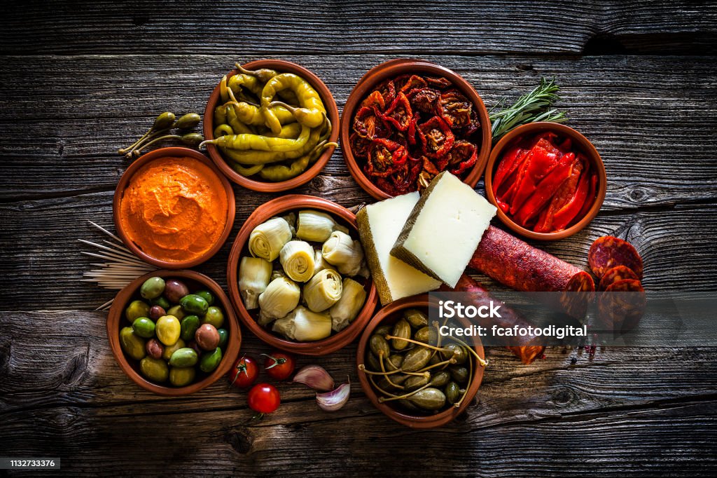 Tapas: comida típica española filmada desde arriba sobre mesa rústica de madera - Foto de stock de Tapas libre de derechos