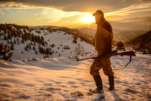istock Hunter standing with his rifle on a snow-covered ridge as the sun is breaking at dawn 1132735872