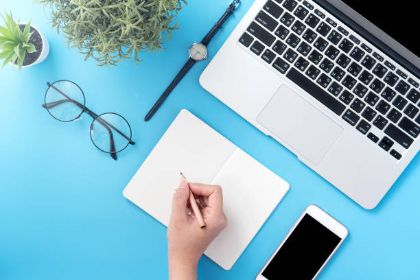 istock A student write on open white book or accounting isolated on a minimal clean blue workplace at home with smartphone and accessories, copy space, flat lay, top view, mock up 1132736040