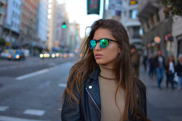 young woman walking in te city urban young girl walking on the Gran Via street in Madrid during sunset wearing sunglasses and black jacket madrid photos stock pictures, royalty-free photos & images