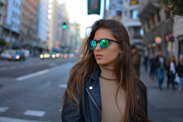 young woman walking in te city urban young girl walking on the Gran Via street in Madrid during sunset wearing sunglasses and black jacket selfie madrid photos stock pictures, royalty-free photos & images