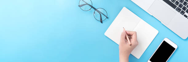 istock A student write on open white book or accounting isolated on a minimal clean blue workplace at home with smartphone and accessories, copy space, flat lay, top view, mock up 1132736057