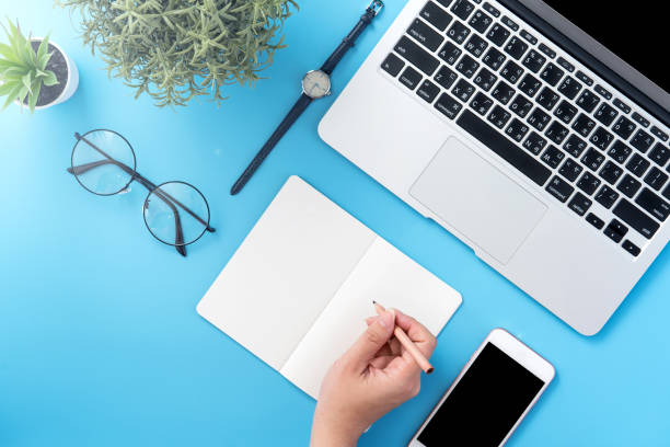 istock A student write on open white book or accounting isolated on a minimal clean blue workplace at home with smartphone and accessories, copy space, flat lay, top view, mock up 1132736091