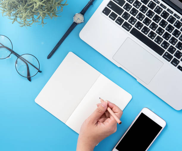 istock A student write on open white book or accounting isolated on a minimal clean blue workplace at home with smartphone and accessories, copy space, flat lay, top view, mock up 1132736106