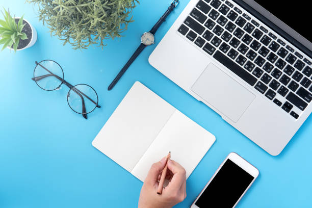 istock A student write on open white book or accounting isolated on a minimal clean blue workplace at home with smartphone and accessories, copy space, flat lay, top view, mock up 1132736271
