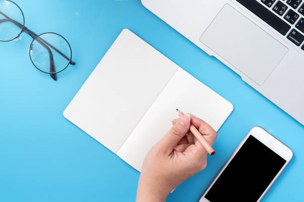 istock A student write on open white book or accounting isolated on a minimal clean blue workplace at home with smartphone and accessories, copy space, flat lay, top view, mock up 1132736294