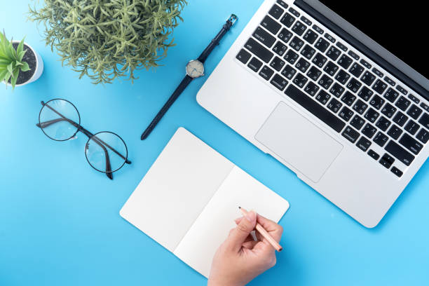 istock A student write on open white book or accounting isolated on a minimal clean blue workplace at home with smartphone and accessories, copy space, flat lay, top view, mock up 1132736350