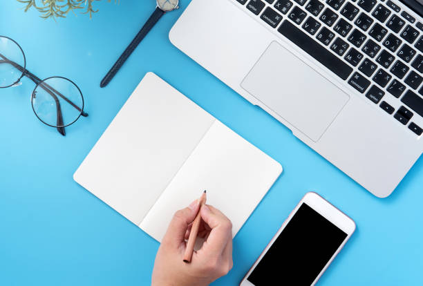 istock A student write on open white book or accounting isolated on a minimal clean blue workplace at home with smartphone and accessories, copy space, flat lay, top view, mock up 1132736385