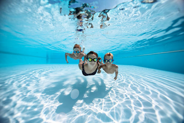 tre bambini felici che nuotano sott'acqua in piscina - swimming pool swimming summer underwater foto e immagini stock