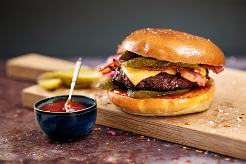 Artisan hamburger with bacon and cheese, gherkins and relish in a brioche bun. Colour, horizontal with some copy space. Please see my other pictures in this series for vegetarian options.