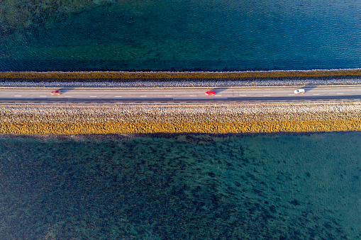 Cars driving on the road on causeway in sunset light, drone point of view, Snaefellsnes Peninsula, Iceland.