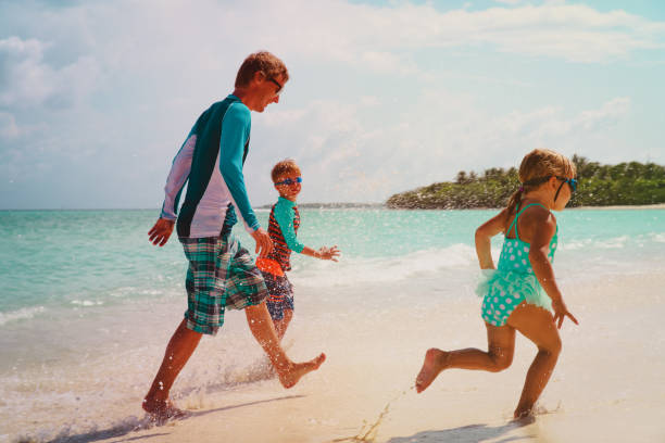 istock father with kids play with water run on beach 1132746647