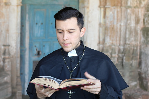 Ethnic young priest reading isolated.