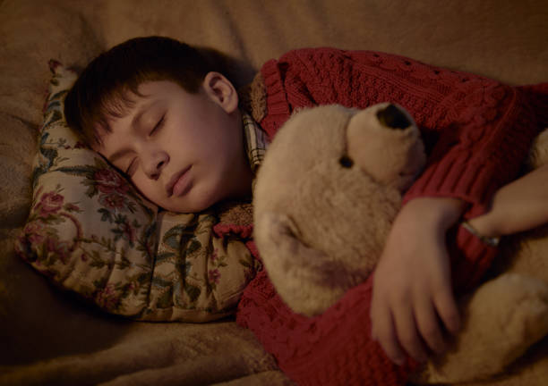 istock boy sleep in bed with bear toy 1132747550