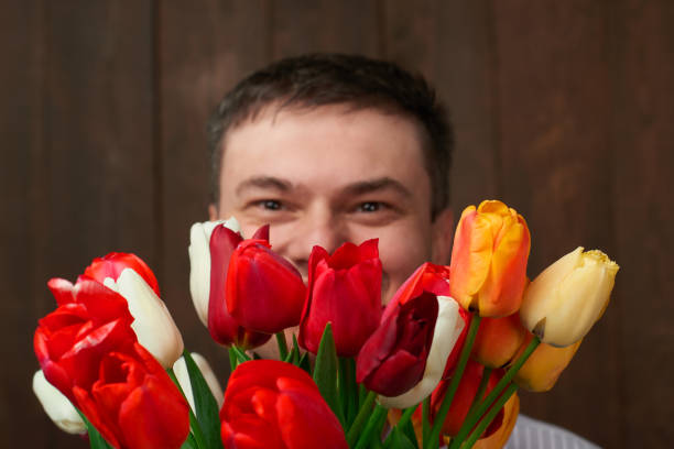 Man face is behind tulip flowers